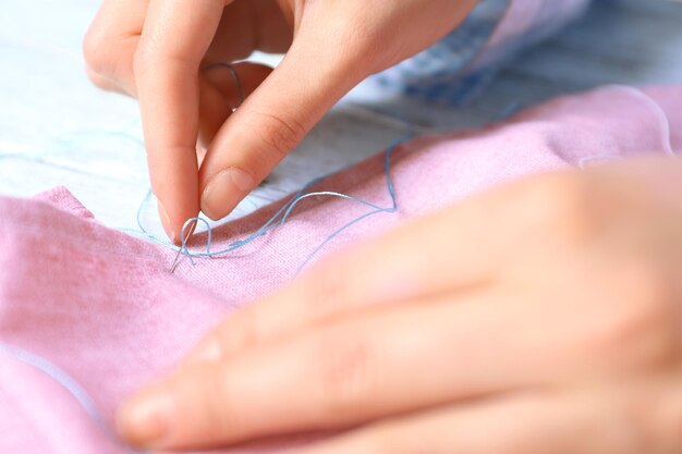 Mâini care cos cu ață colorată